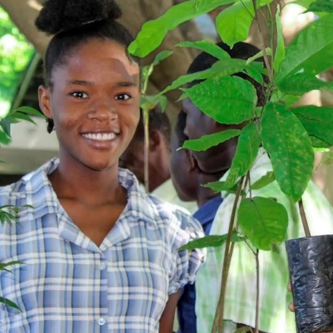 Two women smiling holding a young tree