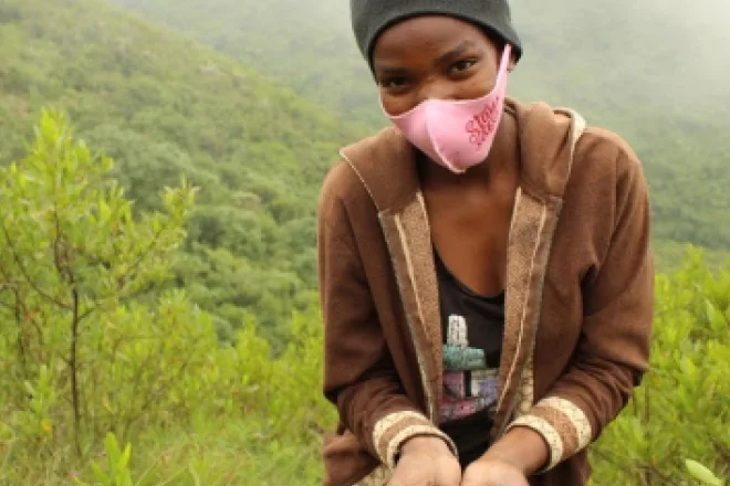 A woman wearing a pink mask with a tree background